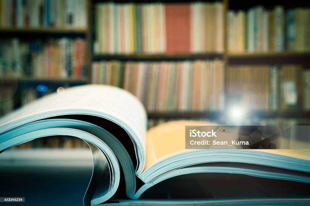 Piles of books and magazines on background of book shelf Piles of books and magazines on background of book shelf, with lens flare Magazine - Publication Stock Photo