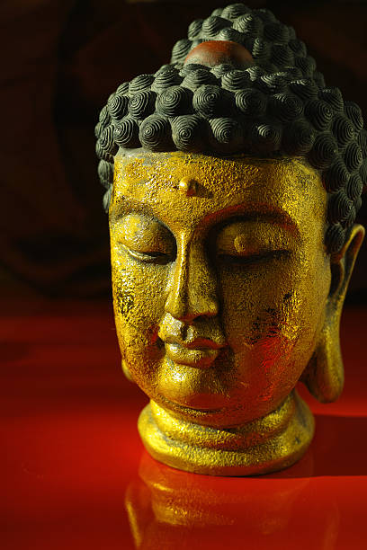 istock Gold Buddha tranquil face on dark red background, copy space 613247152