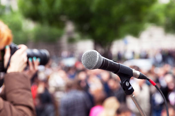 istock Microphone in focus, blurred female photographer at work in the background 613247572