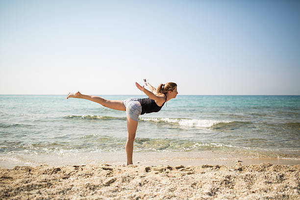 istock young woman exercises on the beach 613248788