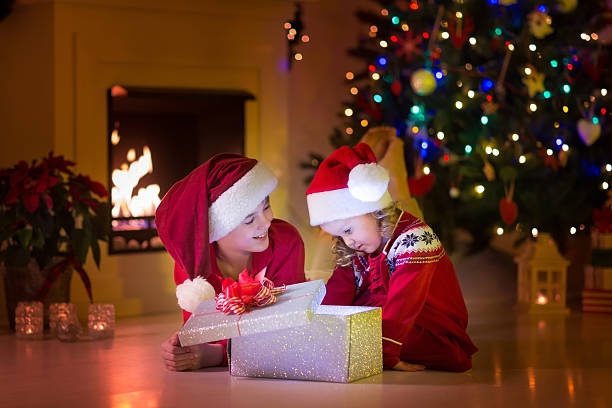 istock Kids opening Christmas presents at fireplace 613249172