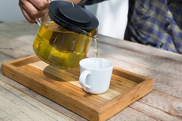 istock pouring hot tea into the white cup 613249898