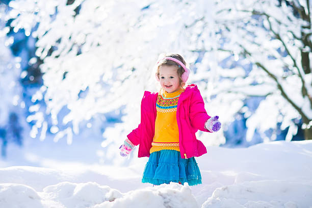 istock Child playing in snowy sunny winter park 613253196