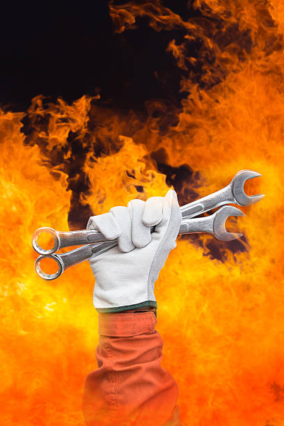 istock Close-up image of human hand holding wrench whit fire background 613254096
