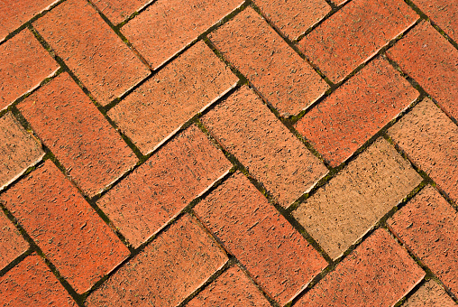 A landscape image of brickwork in a Parquet pattern used on a public pavement.