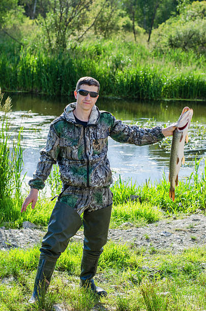 istock The fisherman with the caught  pike 613255732