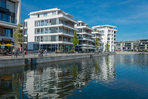 Dortmund, Germany - September 21, 2016: Unna is a town in Nordrhein Westfalen in Germay. The Phoenix lake is a lake build of the former coal mining area, filled with water and it is now a local recreation area. Around the lake people can live in new, modern living houses, driving by sailing boats, shopping in modern shop areas (like photo) or work in office buildings. People walking in the street.