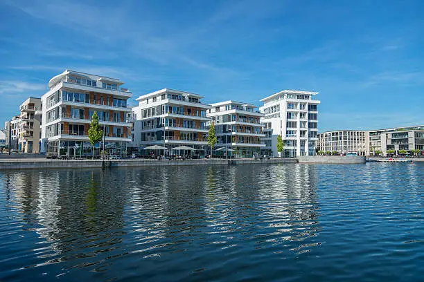 Dortmund is a town in Nordrhein Westfalen in Germay. The Phoenix lake is a lake build of the former coal mining area, filled with water and it is now a local recreation area. Around the lake people can live in new, modern living houses, driving by sailing boats, shopping in modern shop areas (like photo) or work in office buildings. People walking in the street.