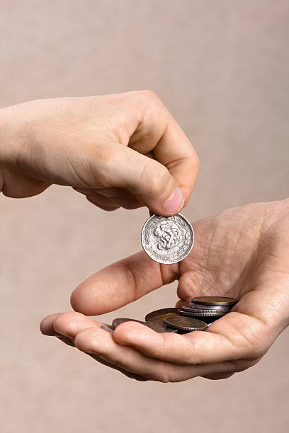 istock hand giving a coin to another person 613305398
