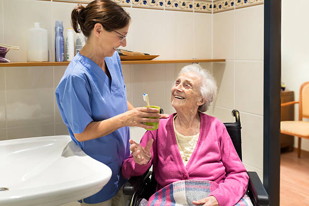 aide-soignant à domicile avec une femme âgée dans la salle de bain - dental assistent photos et images de collection