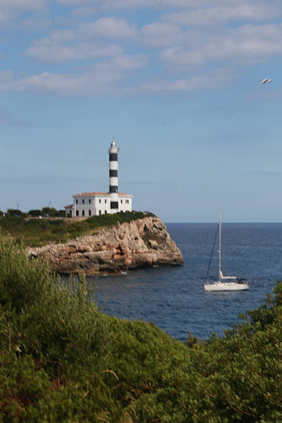 istock Lighthouse with sailing boat passing portrait 613310822