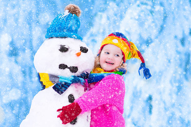 istock Little girl playing with a snowman 613314136