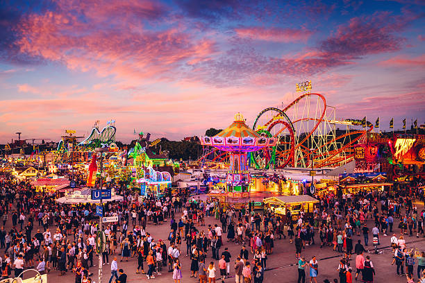 München, Deutschland - 29. September 2016: Besucher bei einem Spaziergang durch das Oktoberfestgelände, Blick auf die rotierende Schaukelfahrt gegen den dunklen Himmel.