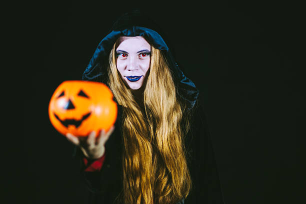 istock Sexy Witch Giving Plastic Pumpkin 613317036