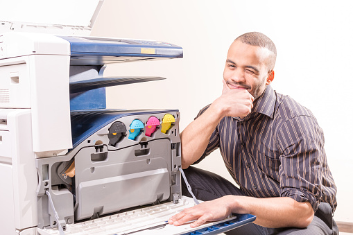 smiling technician sitting near copier
