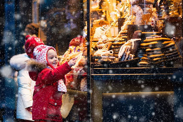 kinder geschwister schauen auf süßigkeiten und gebäck auf weihnachtsmarkt - holiday shopping fotos stock-fotos und bilder