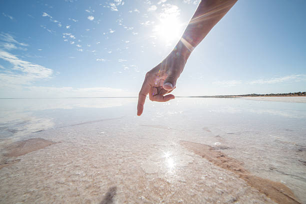 istock Finger touches surface of salted lake 613326692