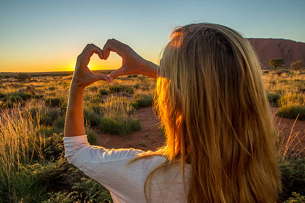 istock View of female framing sunset into heart shape 613327156