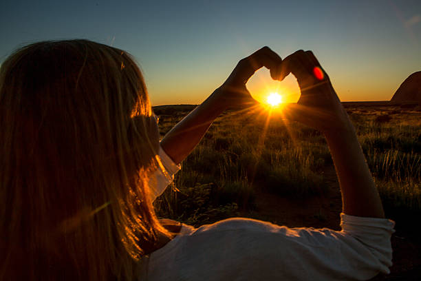 silhouette de la femme faisant cadre de doigt en forme de cœur au coucher du soleil - emu australia northern territory outback photos et images de collection