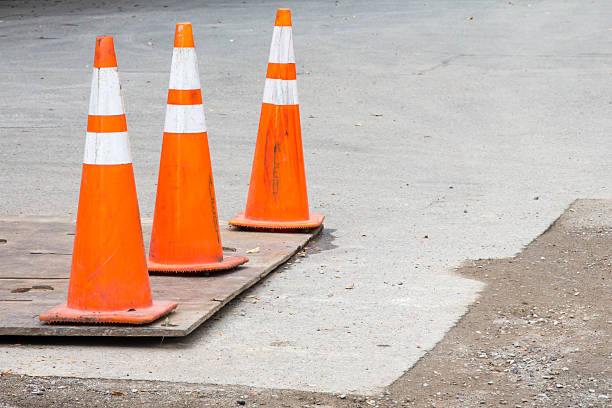 istock Three orange cones on road repair in progress 613328966