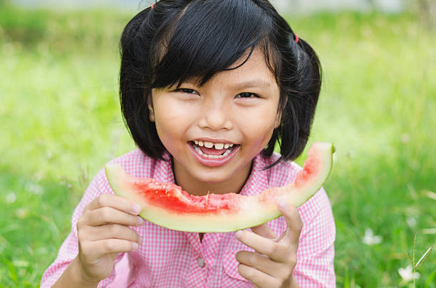 istock cute little girl eating watermelon 613329332