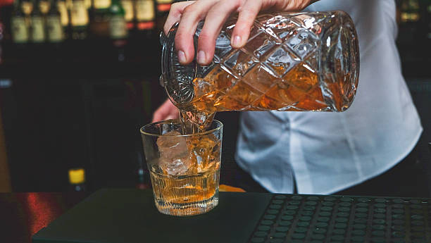 istock Female bartender pouring whiskey at the bar 613330764