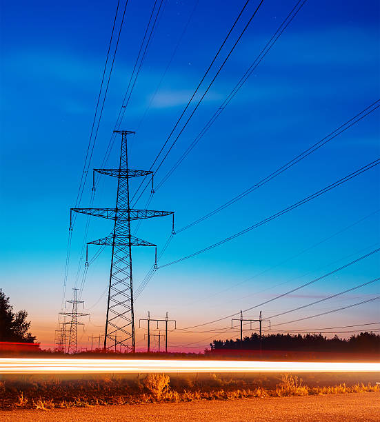 istock Electricity transmission power lines at sunset High voltage tower. 613337180
