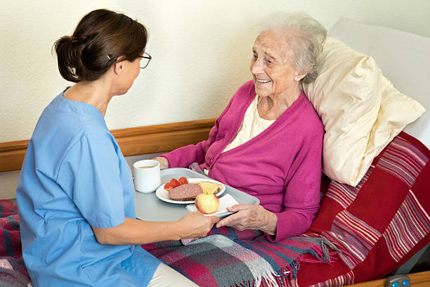 home caregiver with senior adult woman, serving a meal - senior adult nursing home eating home interior imagens e fotografias de stock