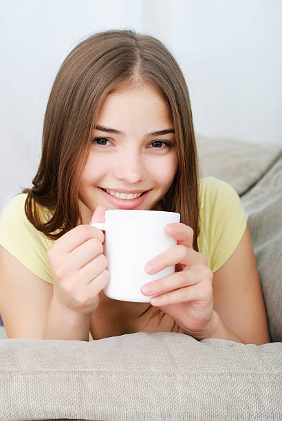 young woman sitting on couch and drinking coffee stock photo