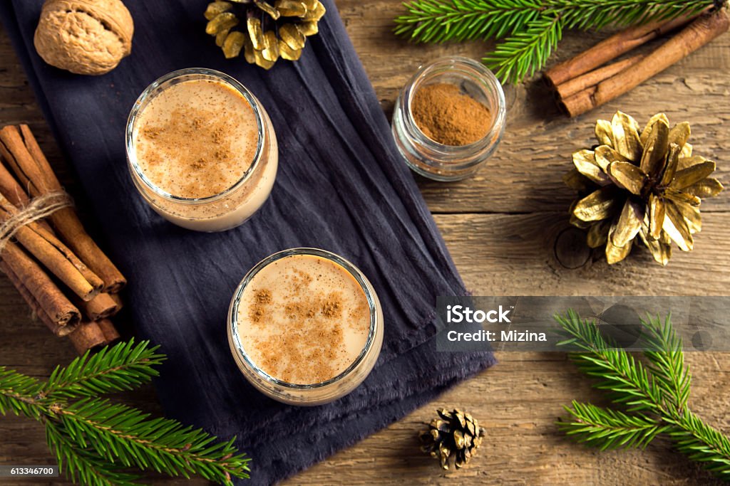 Eggnog for Christmas Eggnog with cinnamon in glasses over rustic wooden background with Christmas decor  - homemade traditional festive drink for Christmas time Alcohol - Drink Stock Photo