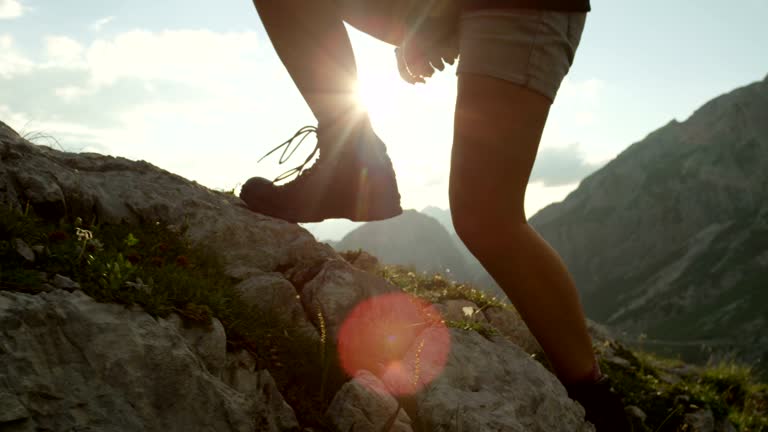 CLOSE UP: Detail of leather mountain shoes and woman climbing steep mountaintop