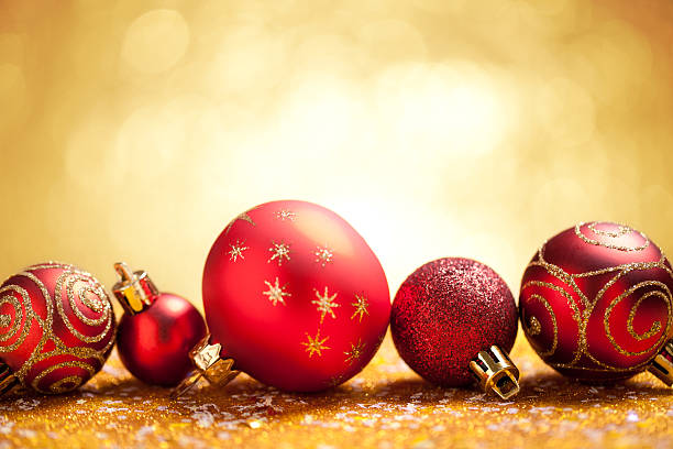 istock Red christmas baubles on gold glitter with yellow background 613516734