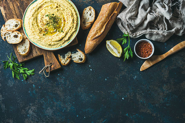 istock Homemade hummus dip with fresh baguette, lemon, herbs and spices 613517270