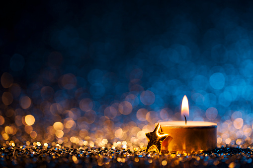 Vela encendida sobre fondo azul desenfocado - Christmas Tea Light photo