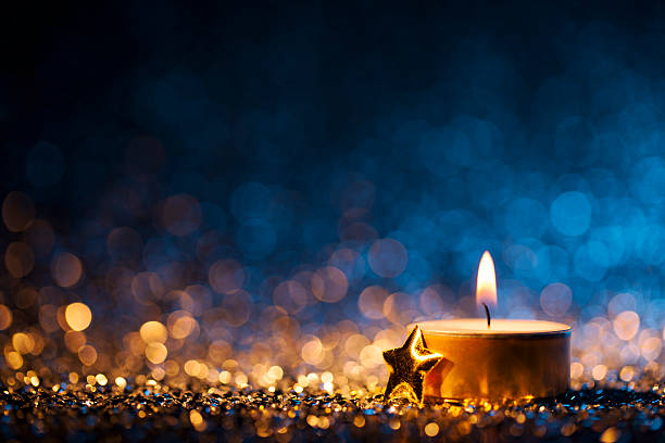 vela encendida sobre fondo azul desenfocado - christmas tea light - christmas candle advent holiday fotografías e imágenes de stock