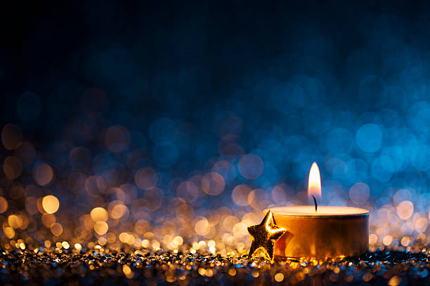 Lighted candle on defocused blue background - Christmas Tea Light Tea light and a golden star on defocused blue and gold background. advent candles stock pictures, royalty-free photos & images