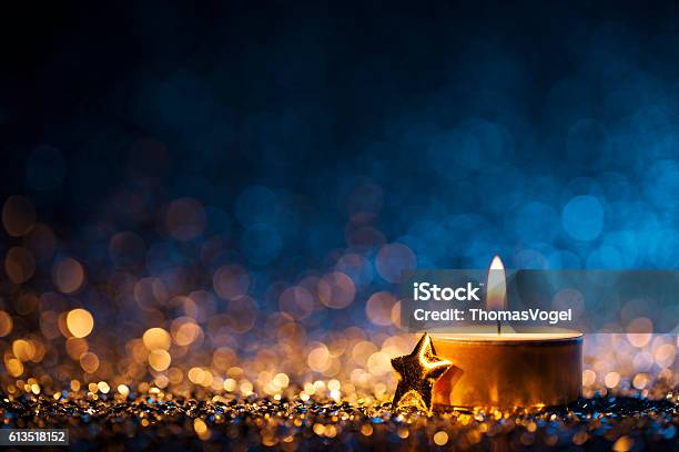 Lighted Candle On Defocused Blue Background Christmas Tea Light Stock Photo - Download Image Now
