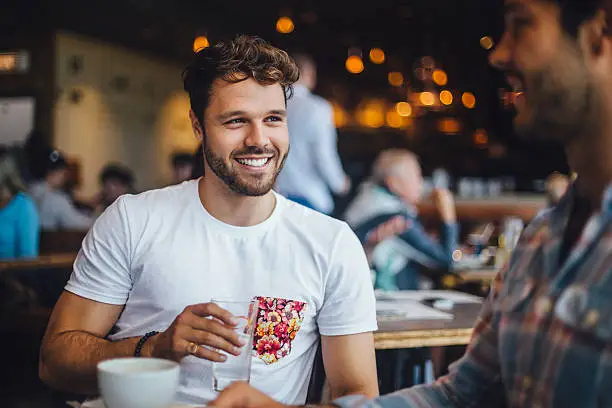 Two male friends talking in a cafe.