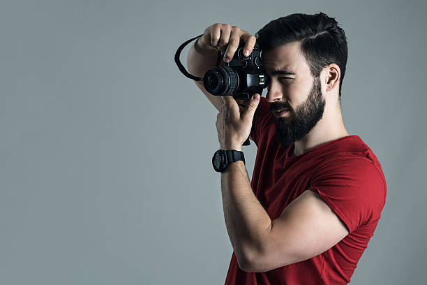 istock Profile view of young man taking photo with digital camera 613519060