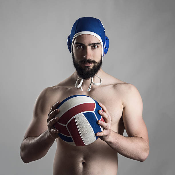 Confident proud portrait of professional water polo player holding ball Confident proud portrait of professional water polo player holding ball looking at camera water polo cap stock pictures, royalty-free photos & images