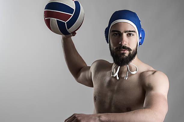 Professional water polo player shooting ball looking at camera Professional water polo player shooting ball looking at camera over gray studio background water polo cap stock pictures, royalty-free photos & images