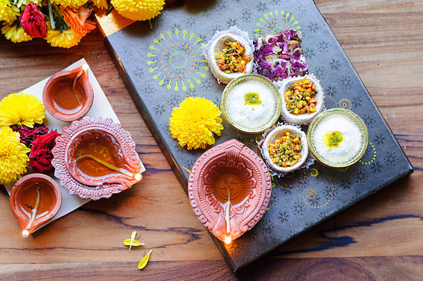 diya lamps lit with flowers and sweets with gift box and on a wooden background with mithai mithai stock pictures, royalty-free photos & images