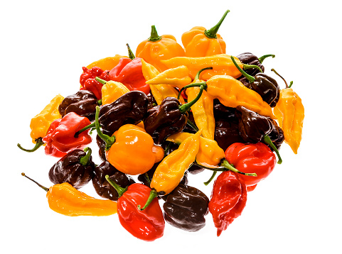Different variety of hot peppers - a bunch of chilies, isolated on white. Hot pepper  Sarit Gat, Red Cherry, Cayenne, Serrano, Caribbean Habanero Orange, Jalapeno, Fatalii Yellow, Trinidad Scorpion Moruga and regular chili.