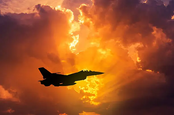 Photo of silhouette F-16 military aircraft flying on sunset