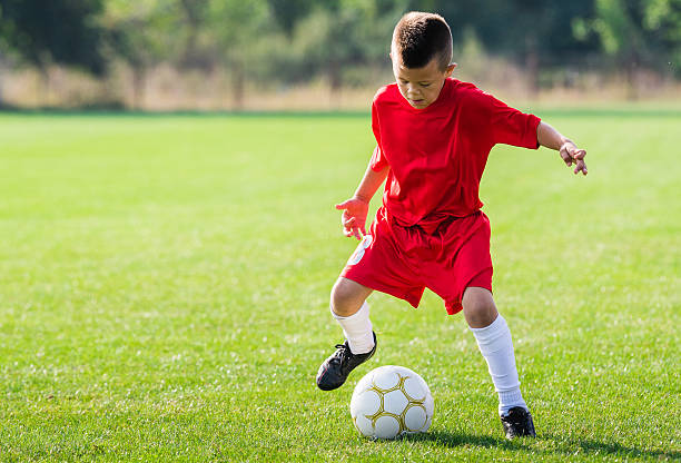 istock Boy kicking soccer ball 613523038