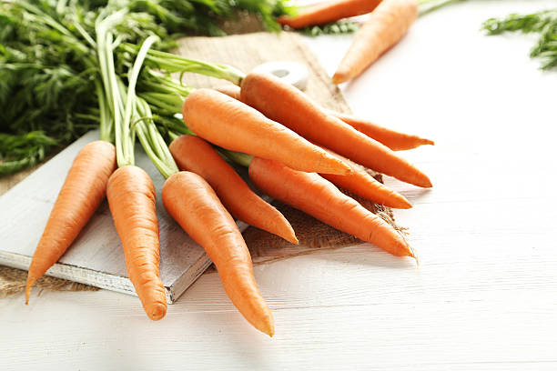istock Fresh and sweet carrots on a white wooden table 613524522