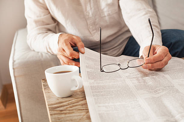 hombre leyendo periódico en casa - reading newspaper break tea fotografías e imágenes de stock