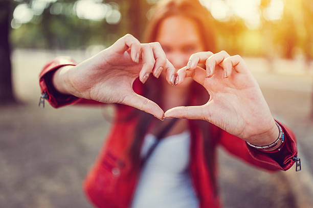 istock Young woman showing heart-shaped symbol 613526894