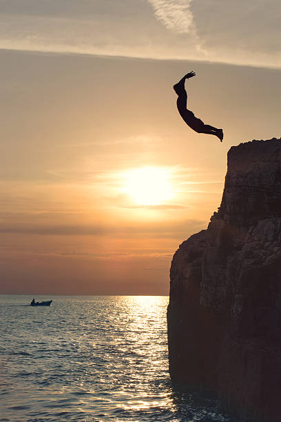 istock boy flying in the sky by jumping from the cliff 613527996