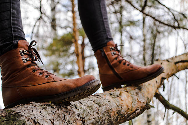 istock Female legs shod in Hiking boots on the forest background 613528962